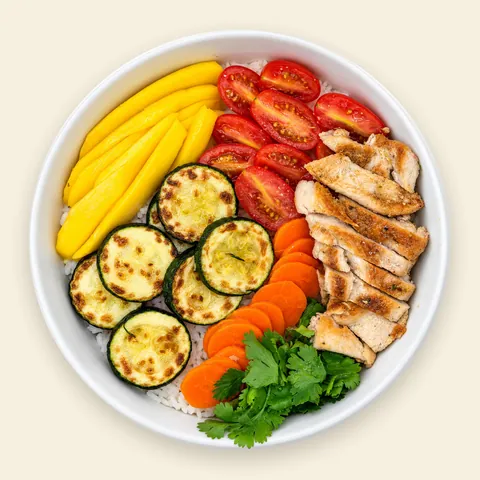 VIVA Pacific Mango Chicken Bowl from VIVA Bowls Miami, seen from above: herb jasmine rice topped with grilled chicken, juicy mango, roasted zucchini, cherry tomatoes and shredded carrot